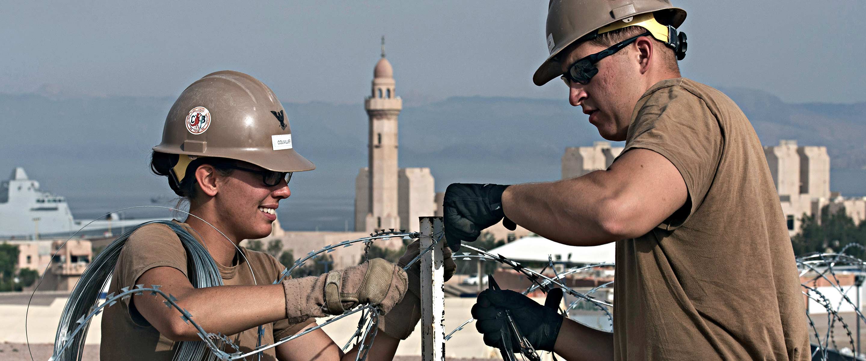 Two current Navy Civil Engineers repairing a fence