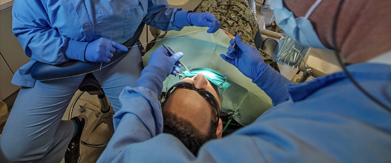 Navy Sailor has his teeth examined and cleaned by Navy Dentists