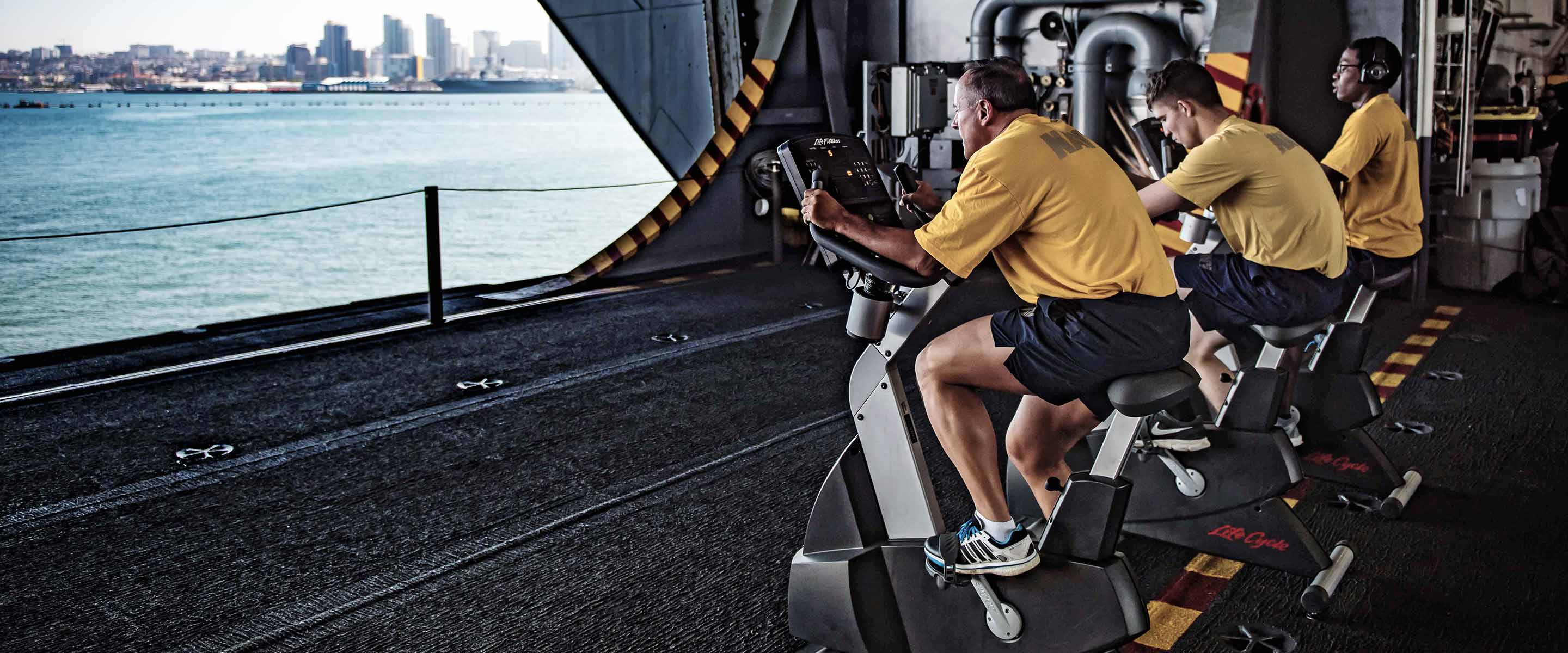 Navy Sailors condition with stationary bikes aboard a ship