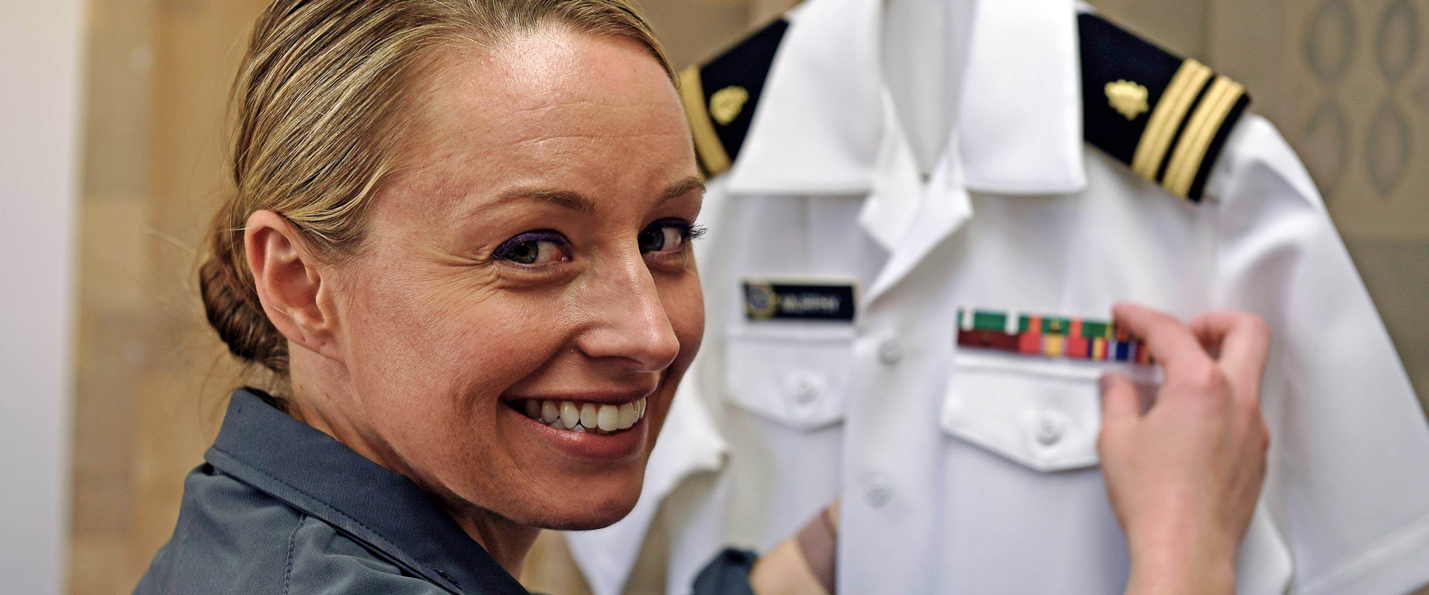 Navy officer places the ribbons and medals on her uniform