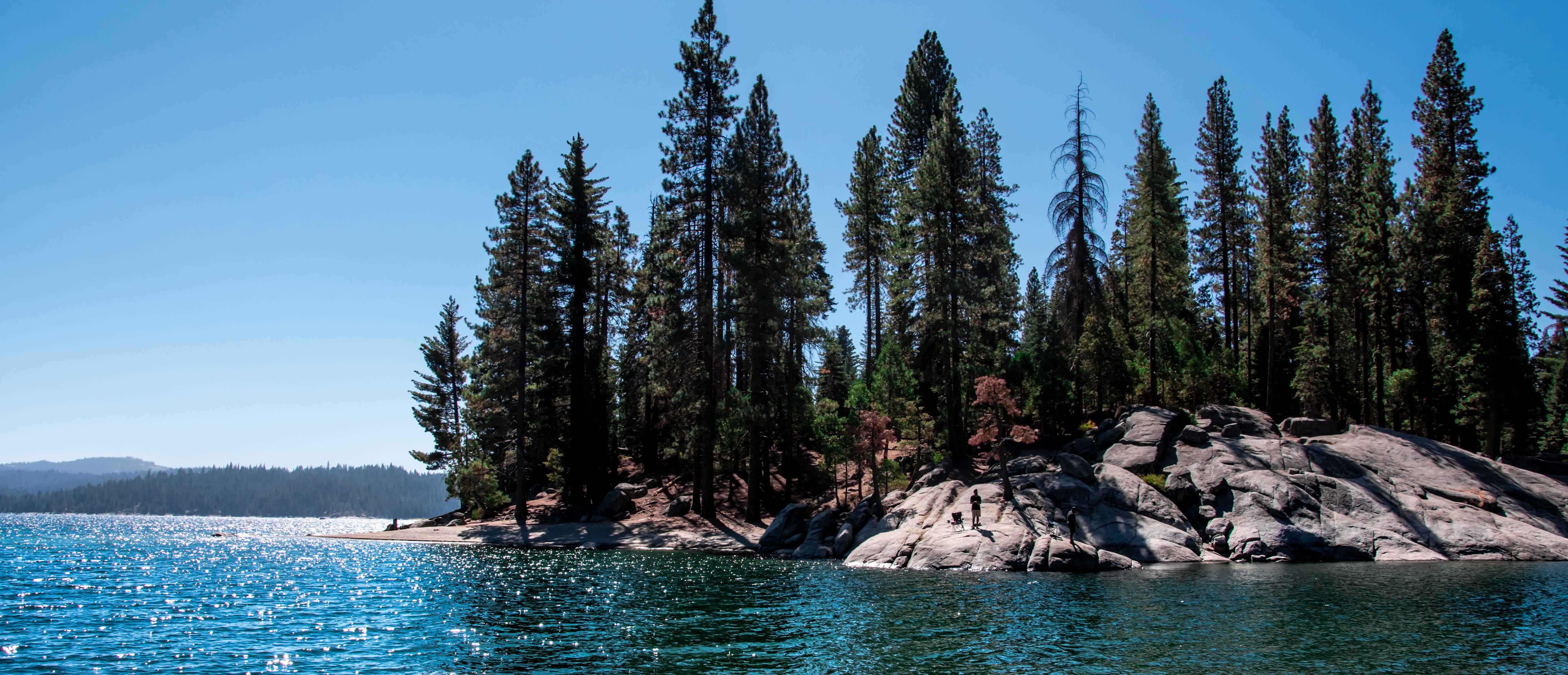 Large body of lake water surrounded by rock formations and evergreen trees