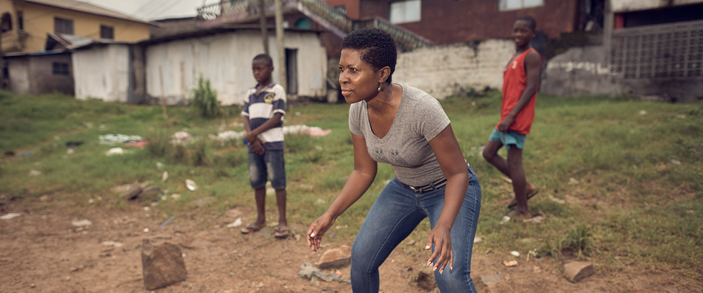 Navy doctor Nehkonti Adams plays a casual game of soccer with two local boys in a grassy lot in Monrovia, Liberia
