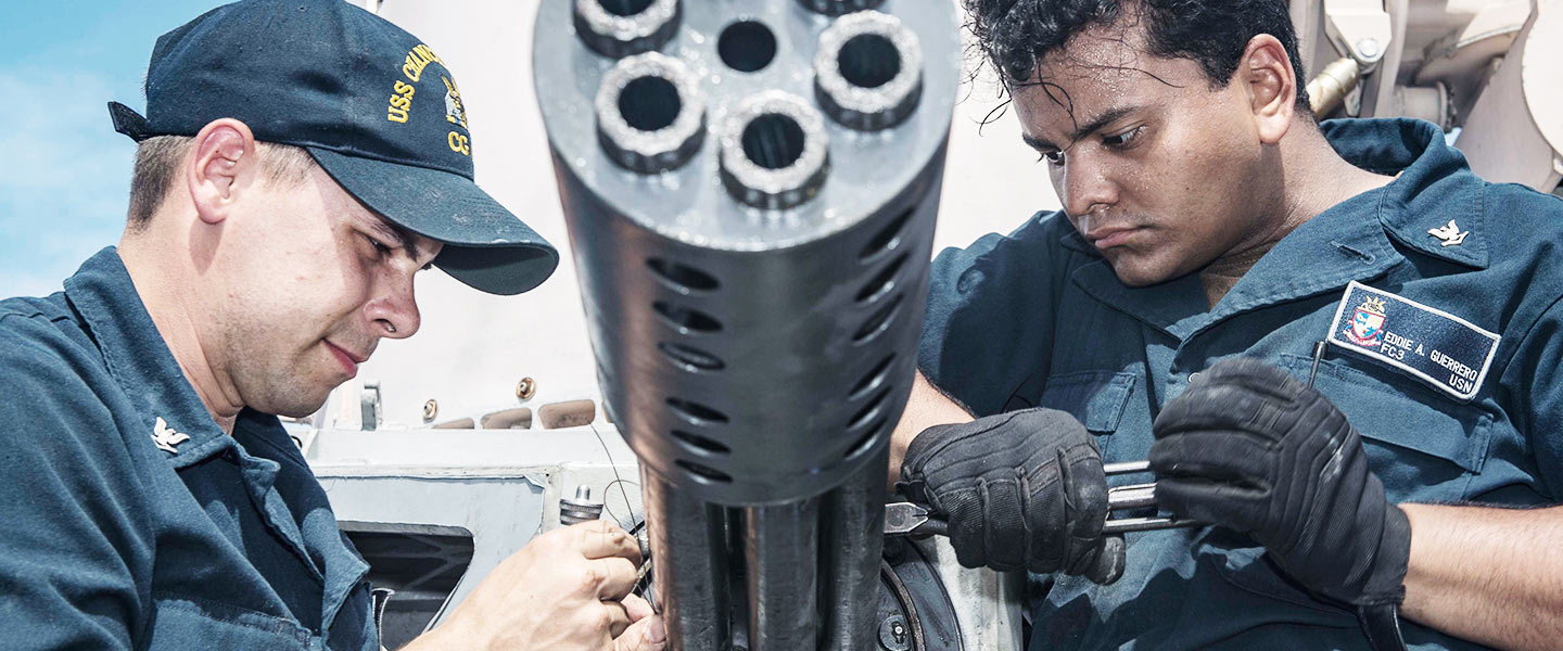 United States Navy Fire Controlmen conduct maintenance on gun barrels aboard the USS Chancellorsville cruiser ship.