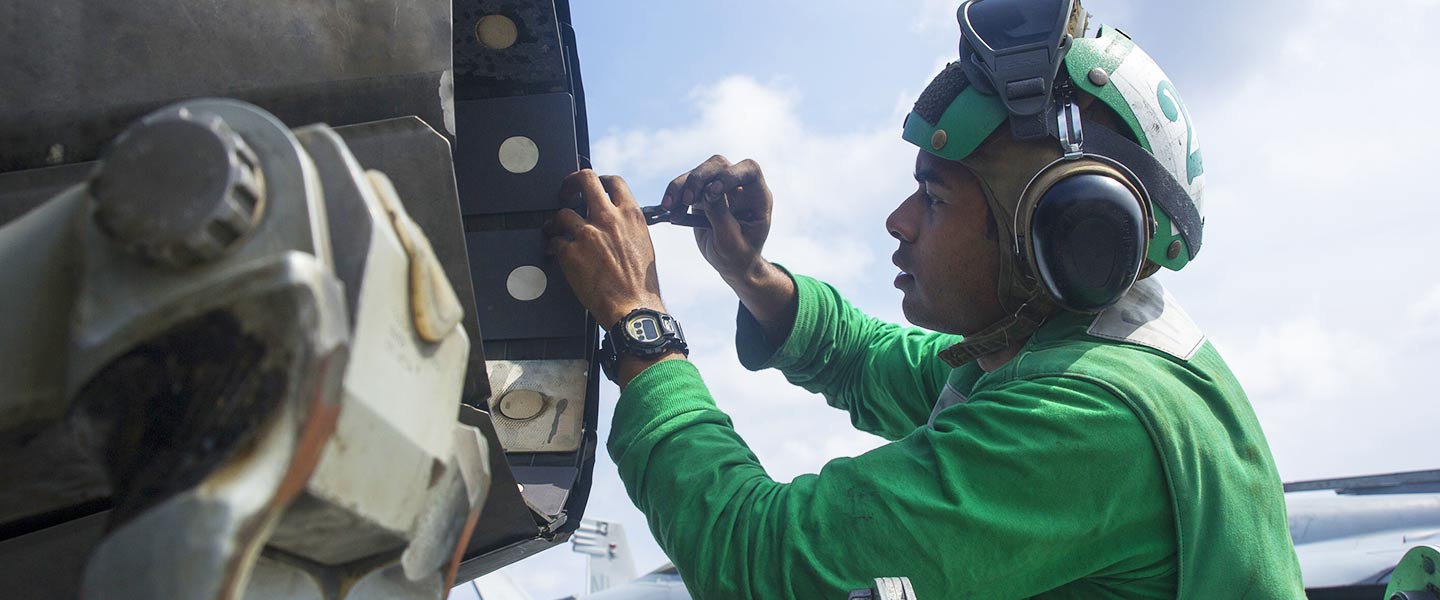 A United States Navy Aviation Machinist's Mate reassembles a variable exhaust nozzle on an F/A-18E Super Hornet on the flight deck of the USS George Washington.