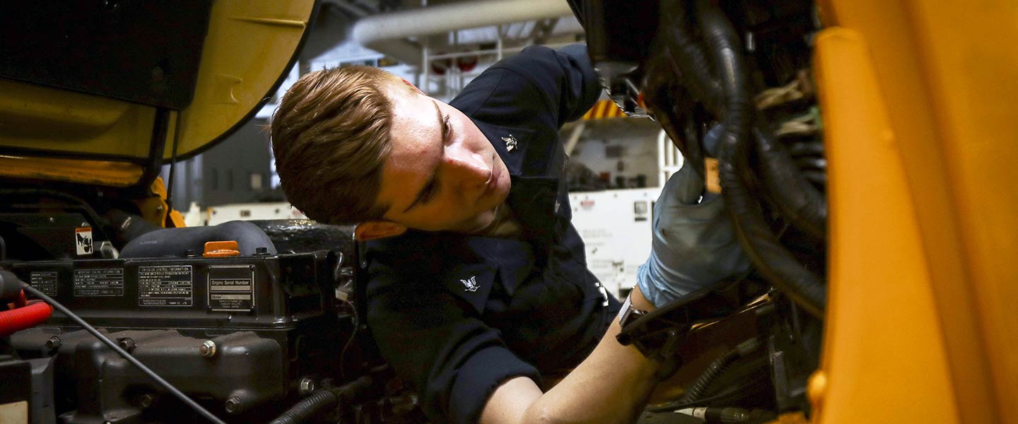A United States Navy Aviation Support Equipment Technician adjusts the hand brake on a forklift aboard the aircraft carrier USS Abraham Lincoln.