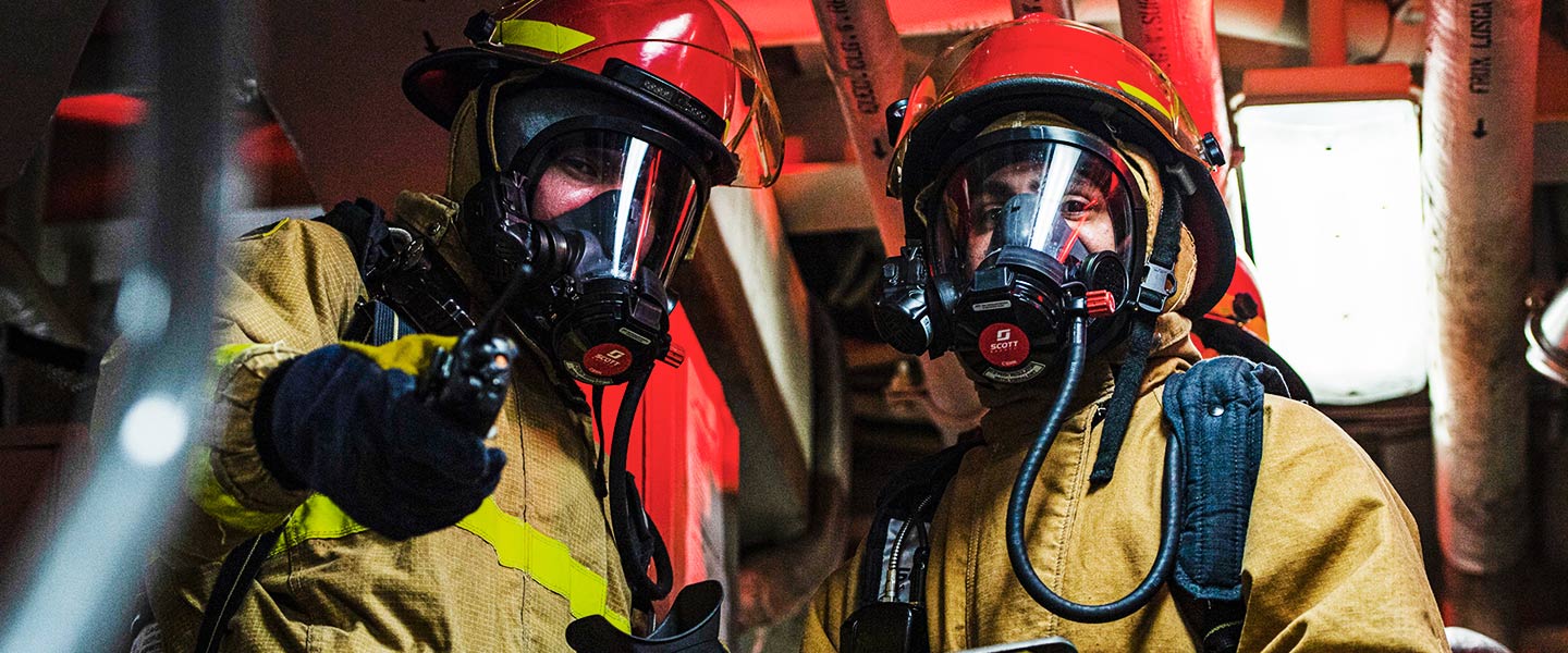 A United States Navy Damage Controlman directs a fellow Sailor to fight a simulated fire during a drill aboard the USS Sterett guided missile destroyer.