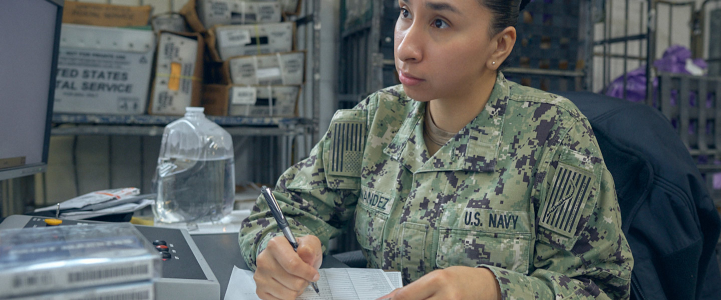 A United States Navy Logistics Specialist maintains logs and records in a Navy Post Office.