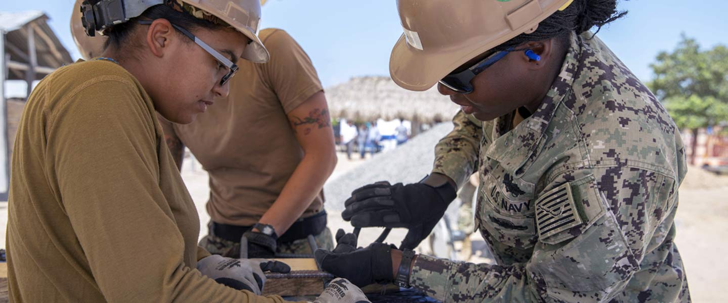 Two United States Navy Utilitiesmen tie rebar during construction of a new school for the indigenous Wayuu people.