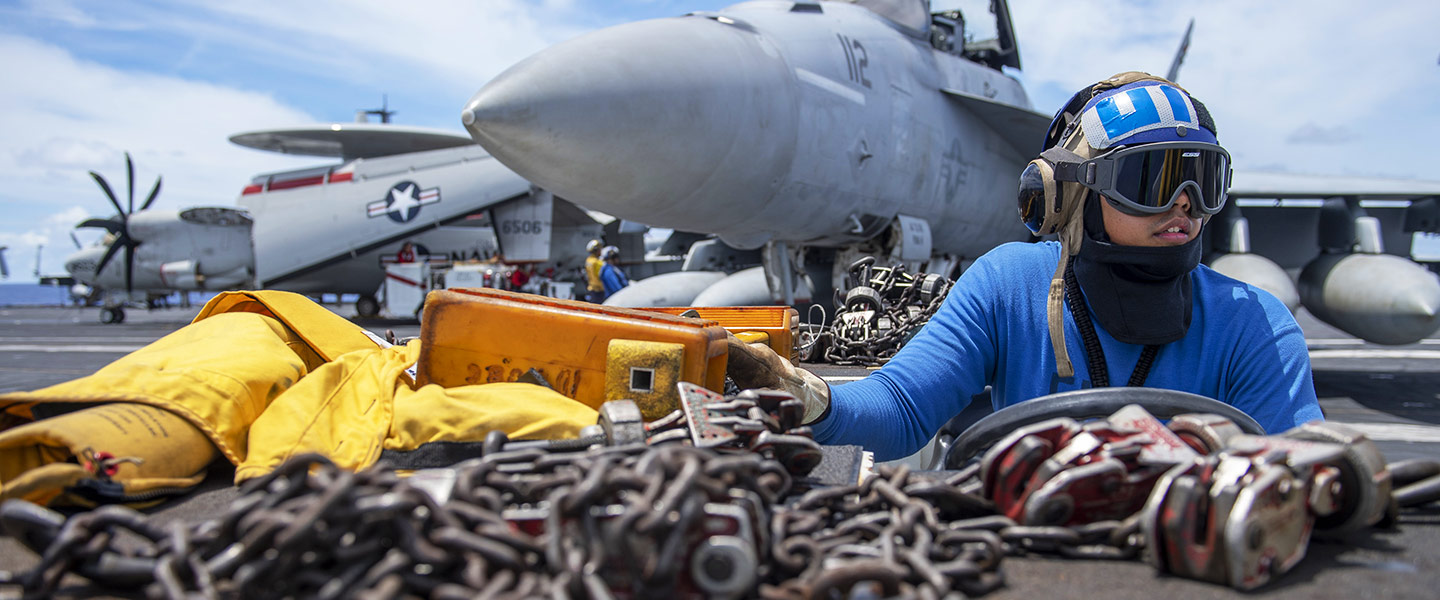 A United States Navy Aviation Boatswain’s Mate – Aircraft Handling signals the pilot of an F/A-18E Super Hornet on the flight deck of the aircraft carrier USS Theodore Roosevelt.