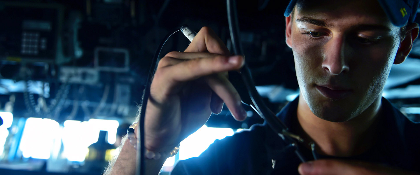 A United States Navy Cryptologic Technician Maintenance repairs a sound-powered phone aboard the USS Ross in support of U.S. national security interests.