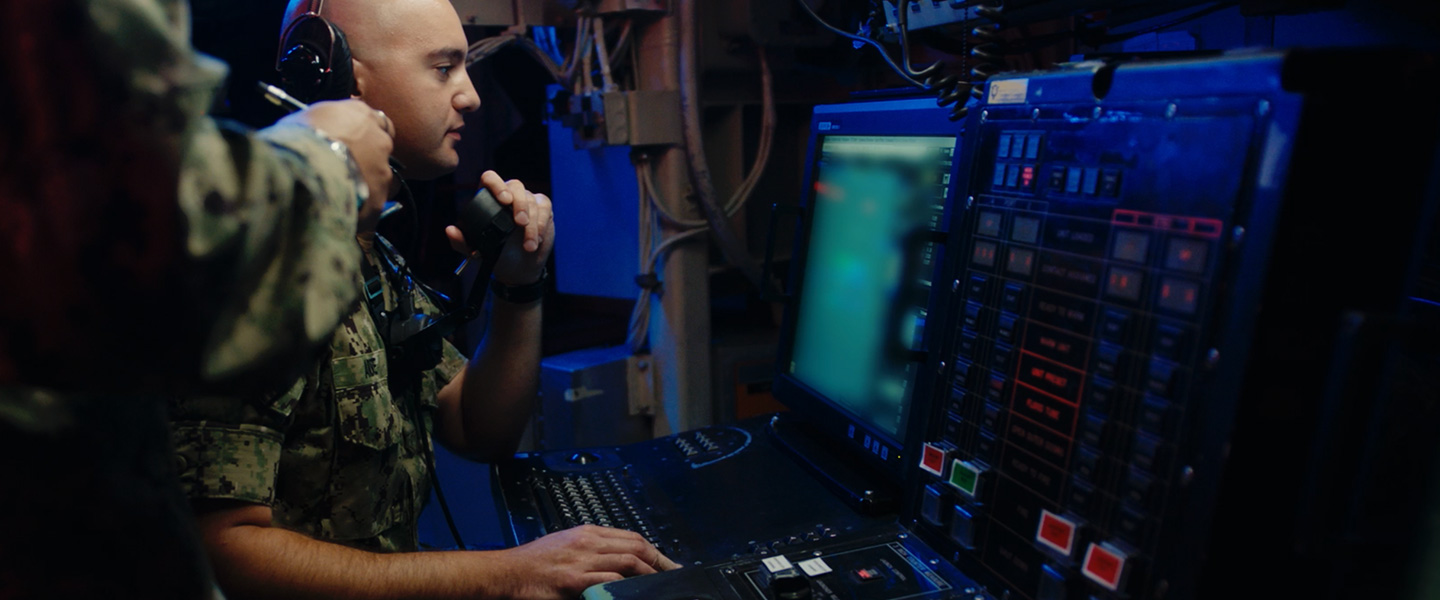 A United States Navy fire control technician operates equipment aboard a submarine during an exercise.