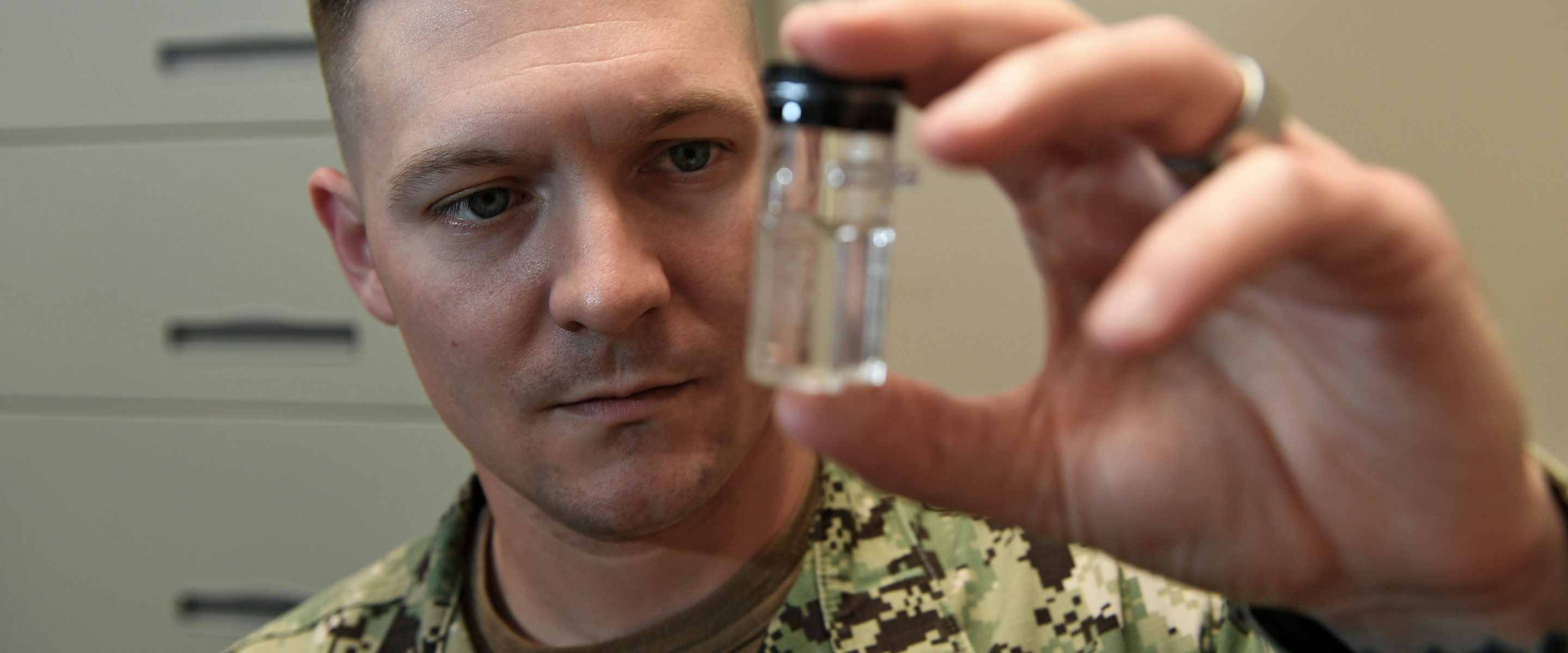 Navy Industrial Hygiene Officer examines a specimen in a glass bottle