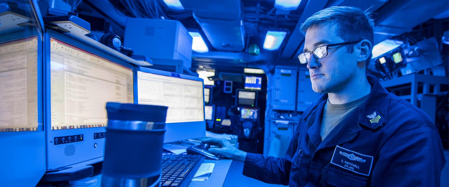 A United States Navy Intelligence Specialist uses the intelligence carry-on program in the command control center aboard the amphibious transport dock ship USS John P. Murtha.