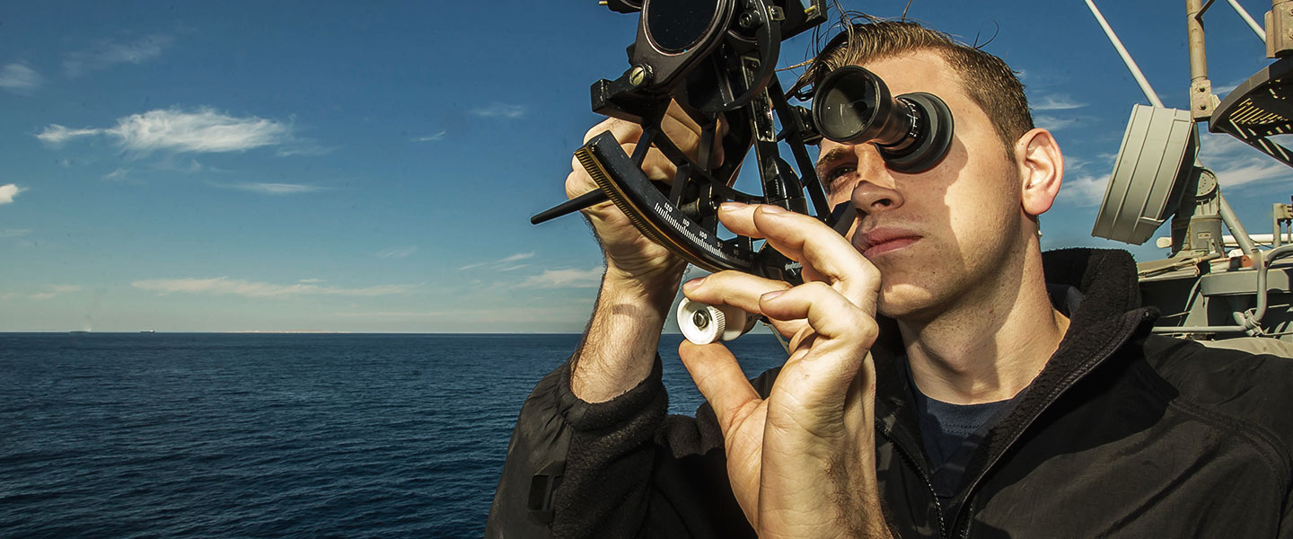 A United States Navy Quartermaster uses a sextant to the measure the angle of the sun on the USS San Jacinto cruiser.