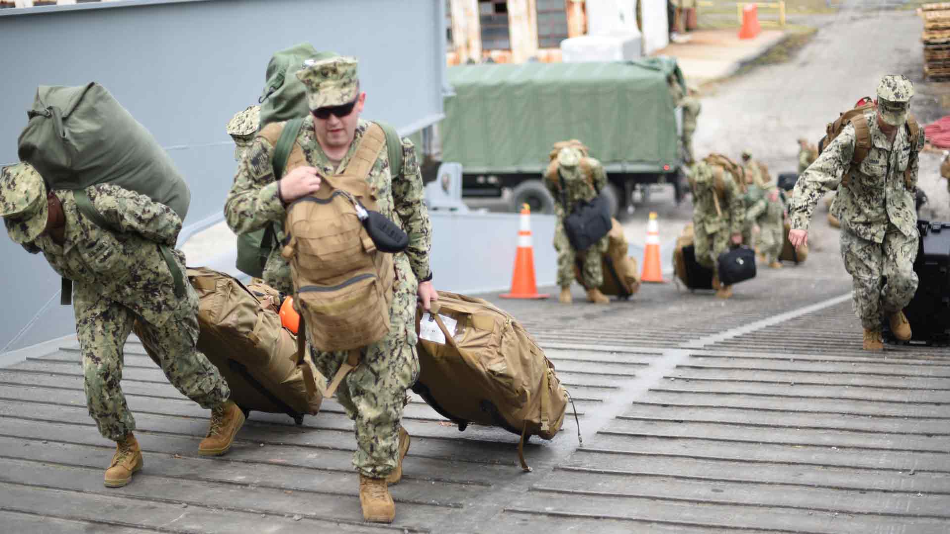 United States Navy Sailors carry their bags onto the ship as they go to sea