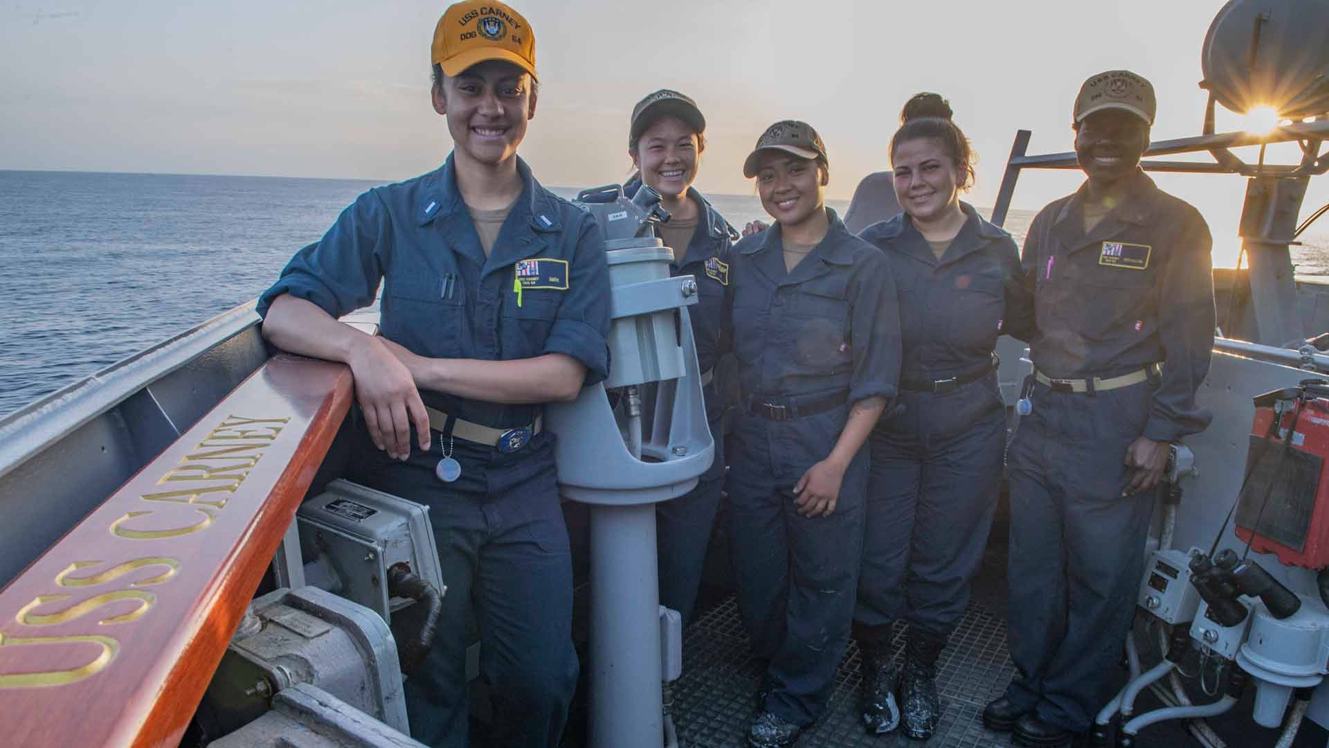 Diverse women U.S. Navy Sailors pose for a photo aboard a Navy ship while out to sea