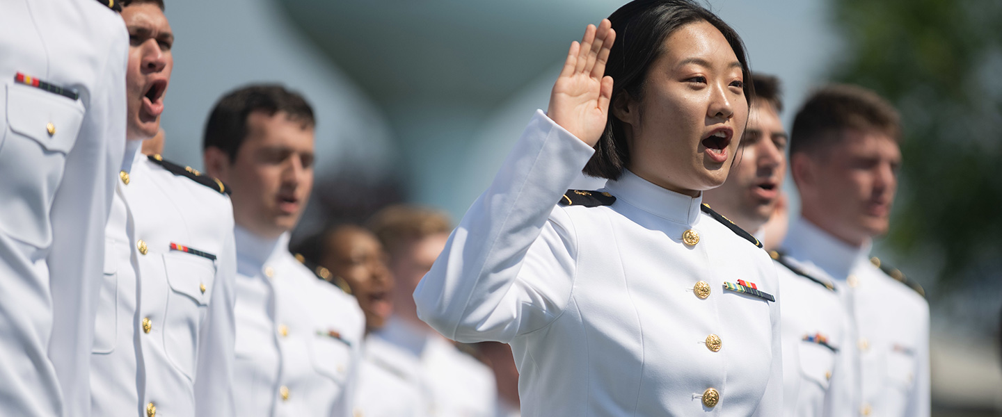 United States Naval Academy midshipmen are commissioned as Navy Ensigns during a graduation ceremony.
