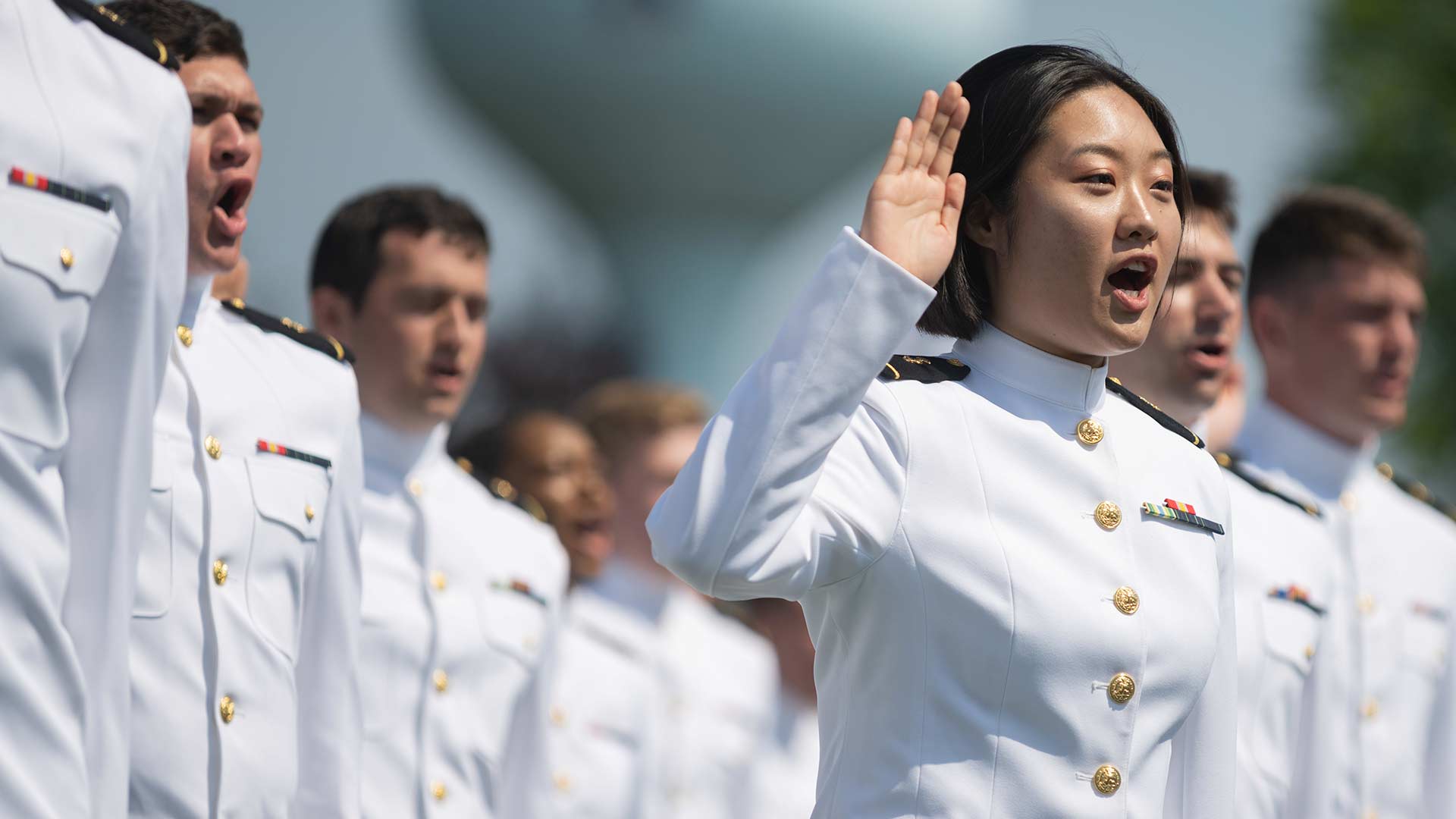 United States Naval Academy midshipmen are commissioned as Navy Ensigns during a graduation ceremony.