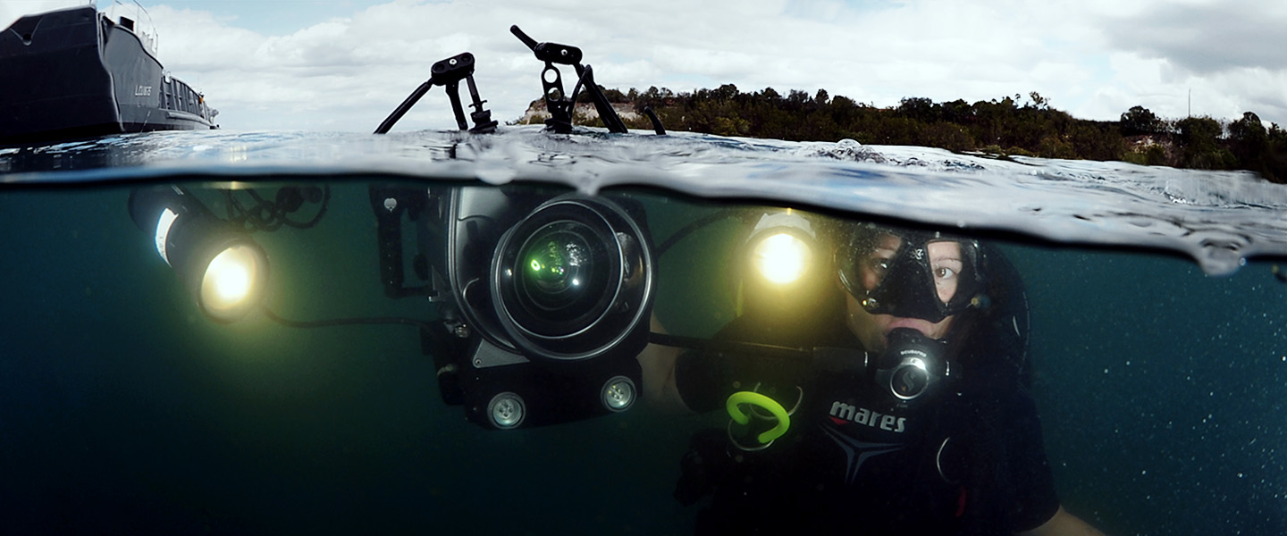 A Navy Sailor takes underwater photographs in full scuba diving gear and high-tech photo equipment.