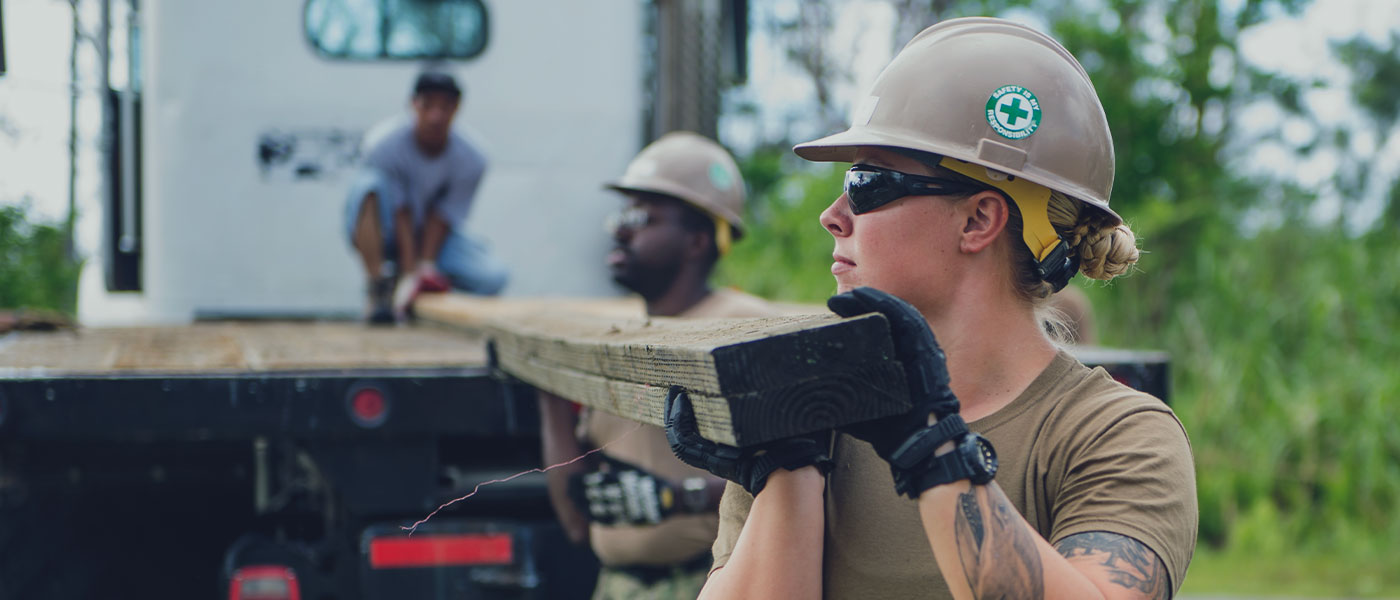 A team of Navy Sailors unload lumber for a building project.