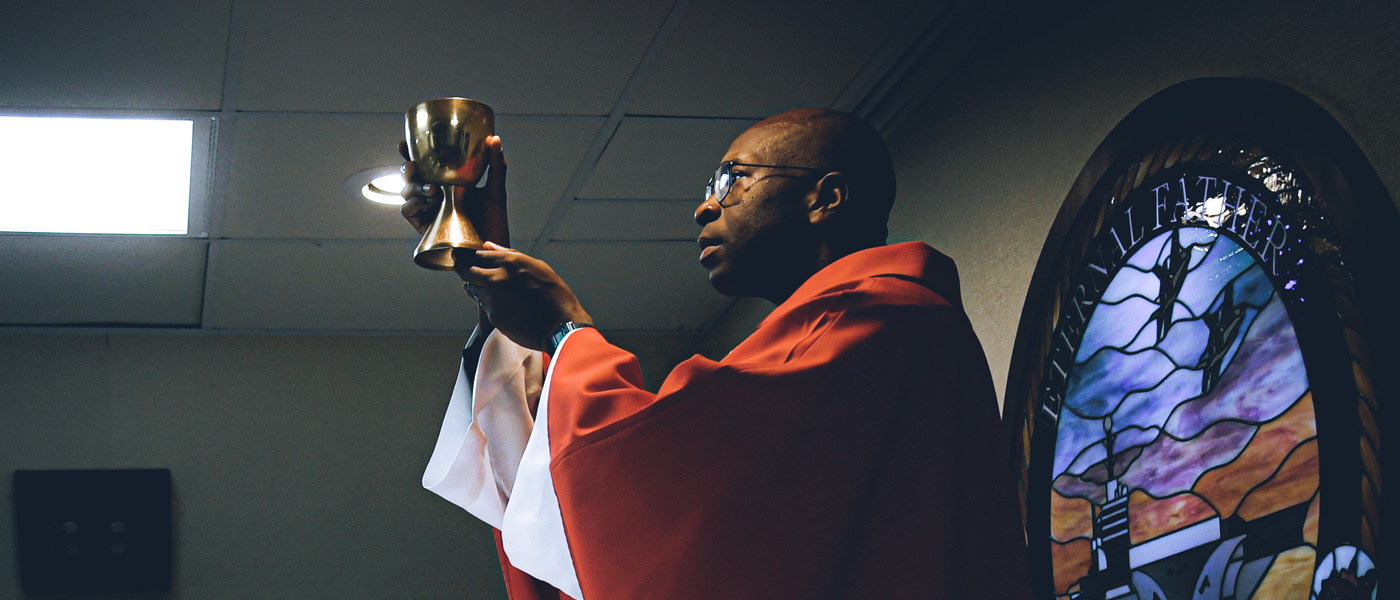 A United States Navy Chaplain raises a communion chalice during a church service at sea.