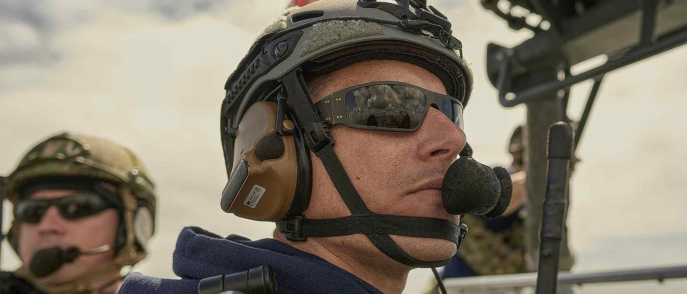 A United States Navy special operations Sailor communicates through a headpiece while standing watch on the deck of a Navy vessel.