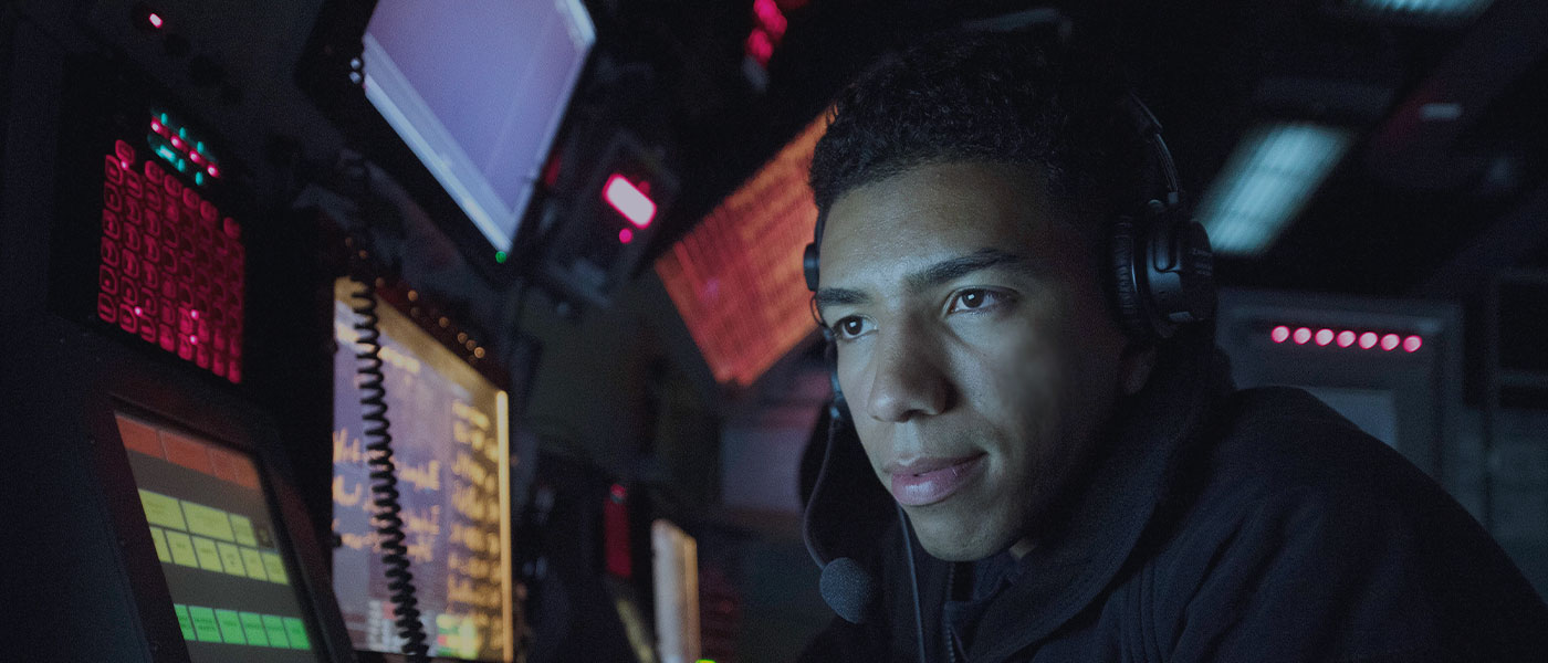 A Navy technology specialist monitors navigation equipment aboard a United States Navy vessel.