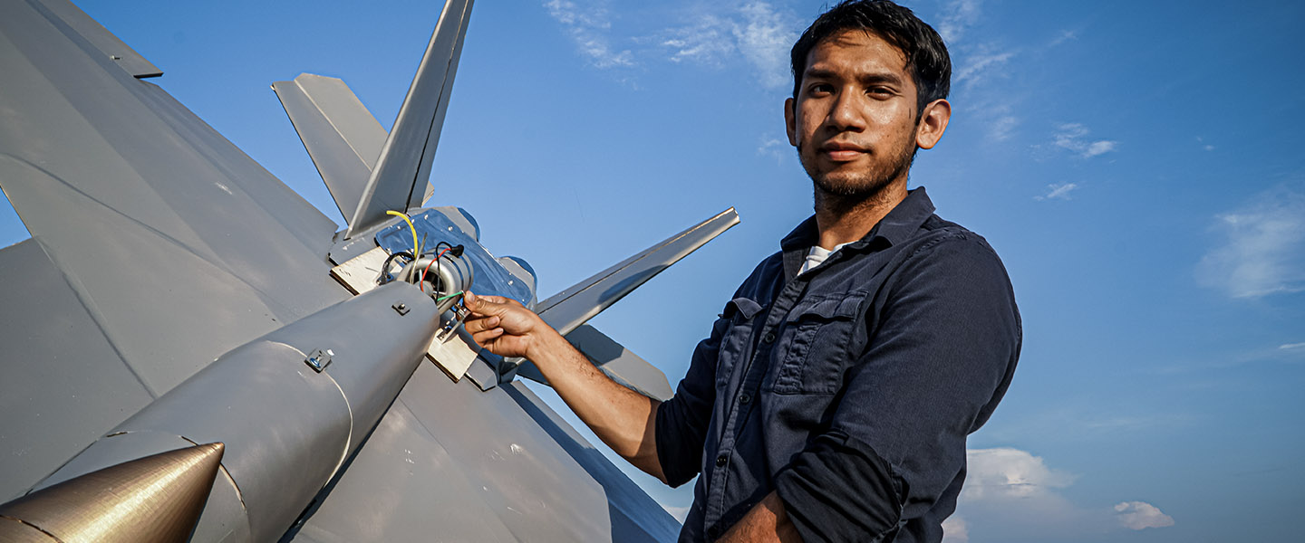 YouTube Creator Peter Sripol displays a large model F-18 as part of the US Navy's Sailor VS series.