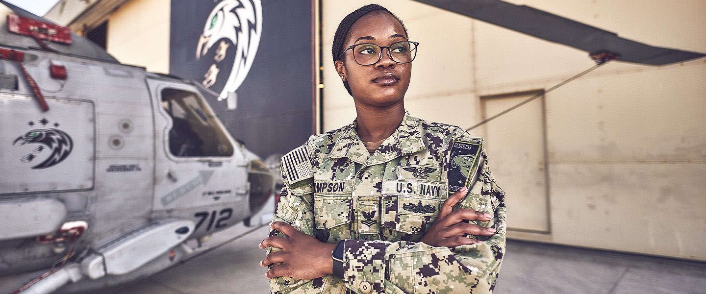 A U.S. Navy Sailor stands in front of a MH-60R helicopter from the HSM-71 Raptors in San Diego, CA. 