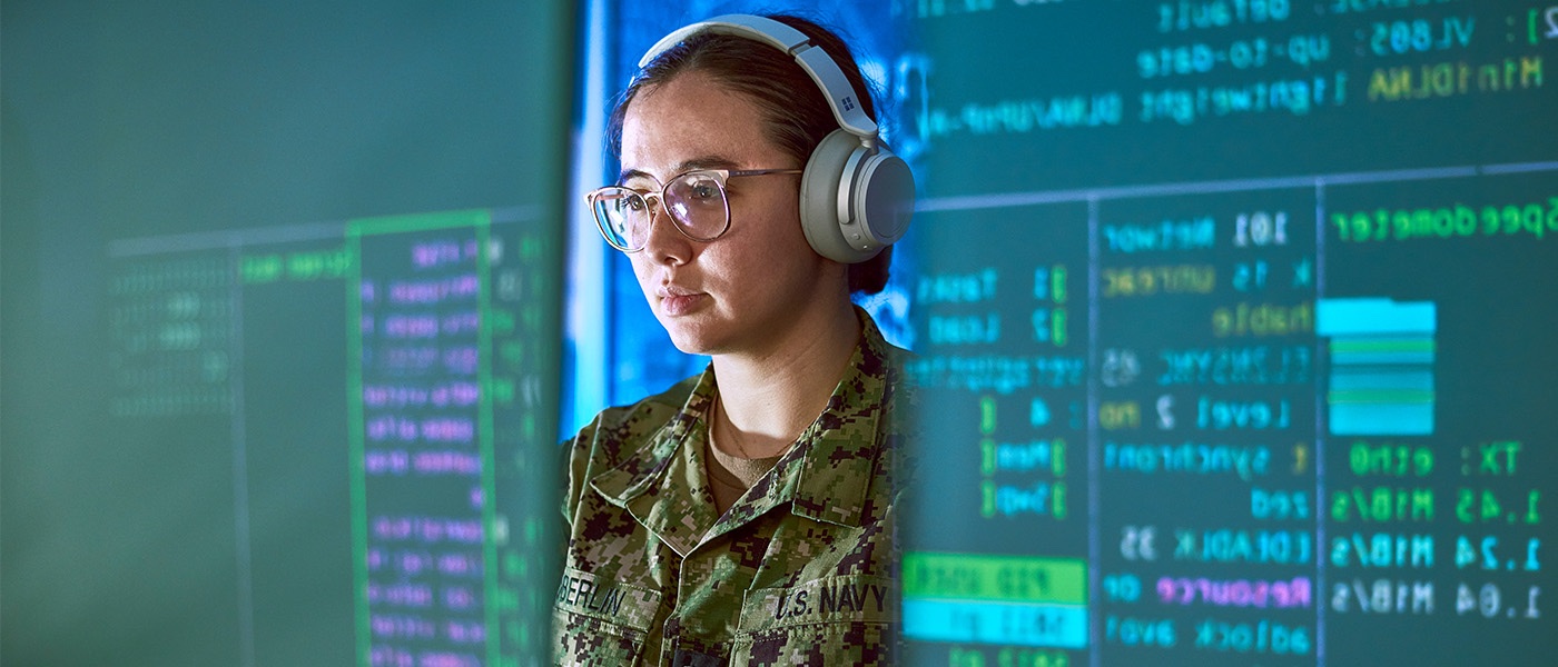 ENS Marie Oberlin sits at a computer with headphones on.