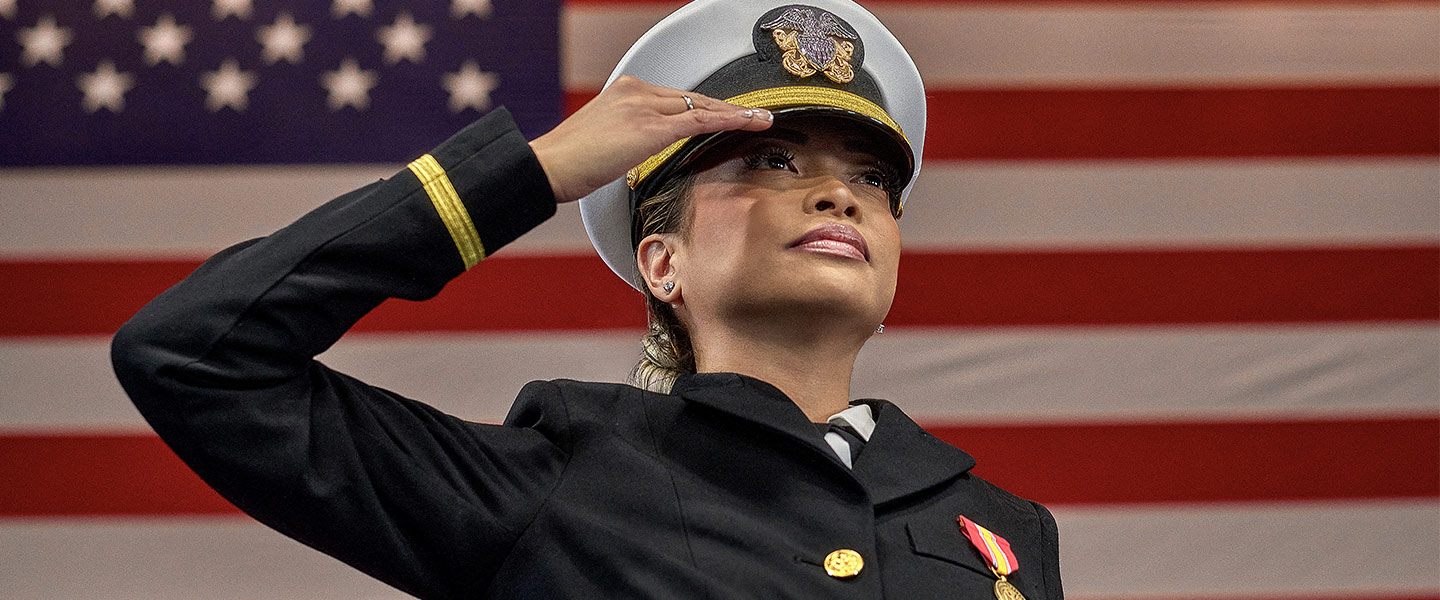 Navy Reserve Sailor saluting in front of American Flag.