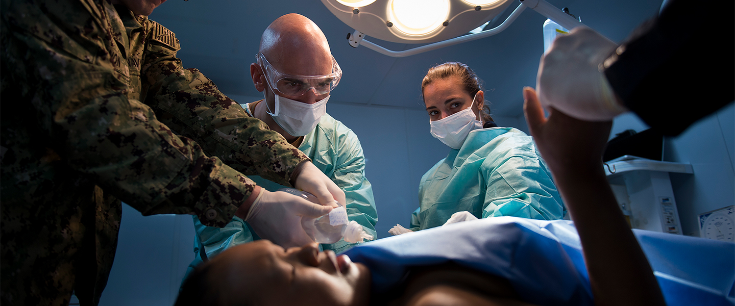 Navy doctor examining a child's ear with an otoscope, promoting Navy medicine careers.