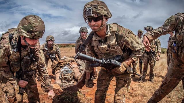 Special Amphibious Reconnaissance Corpsmen conduct Tactical Combat Casualty Care training, assisting soldiers in a simulated battlefield medical scenario.