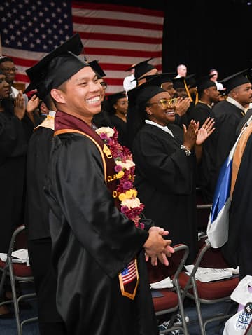 A student in the U.S. Navy is wearing a cap and gown during a college graduation ceremony.