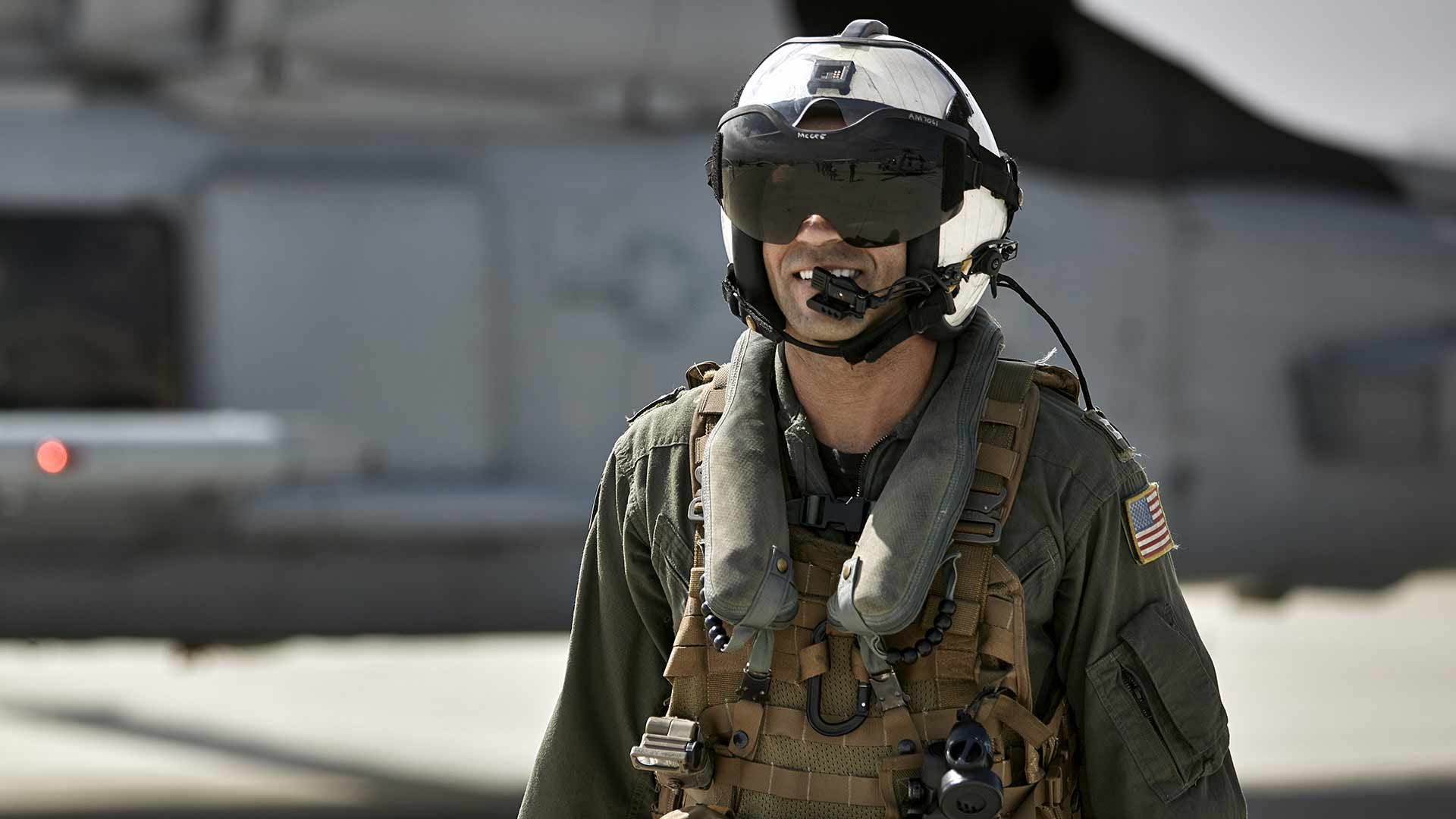 Navy fighter pilot Aeric McGee walks prepares to board a fighter jet in full aviation gear aboard a US aircraft carrier. 