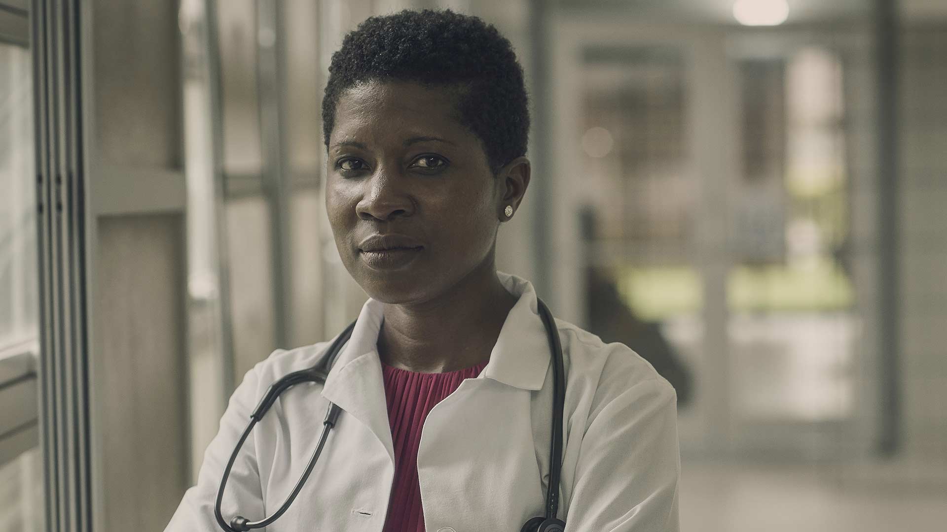 Navy infectious disease doctor Nehkonti Adams poses for a photo wearing white lab coat and stethoscope in a Navy medical facility