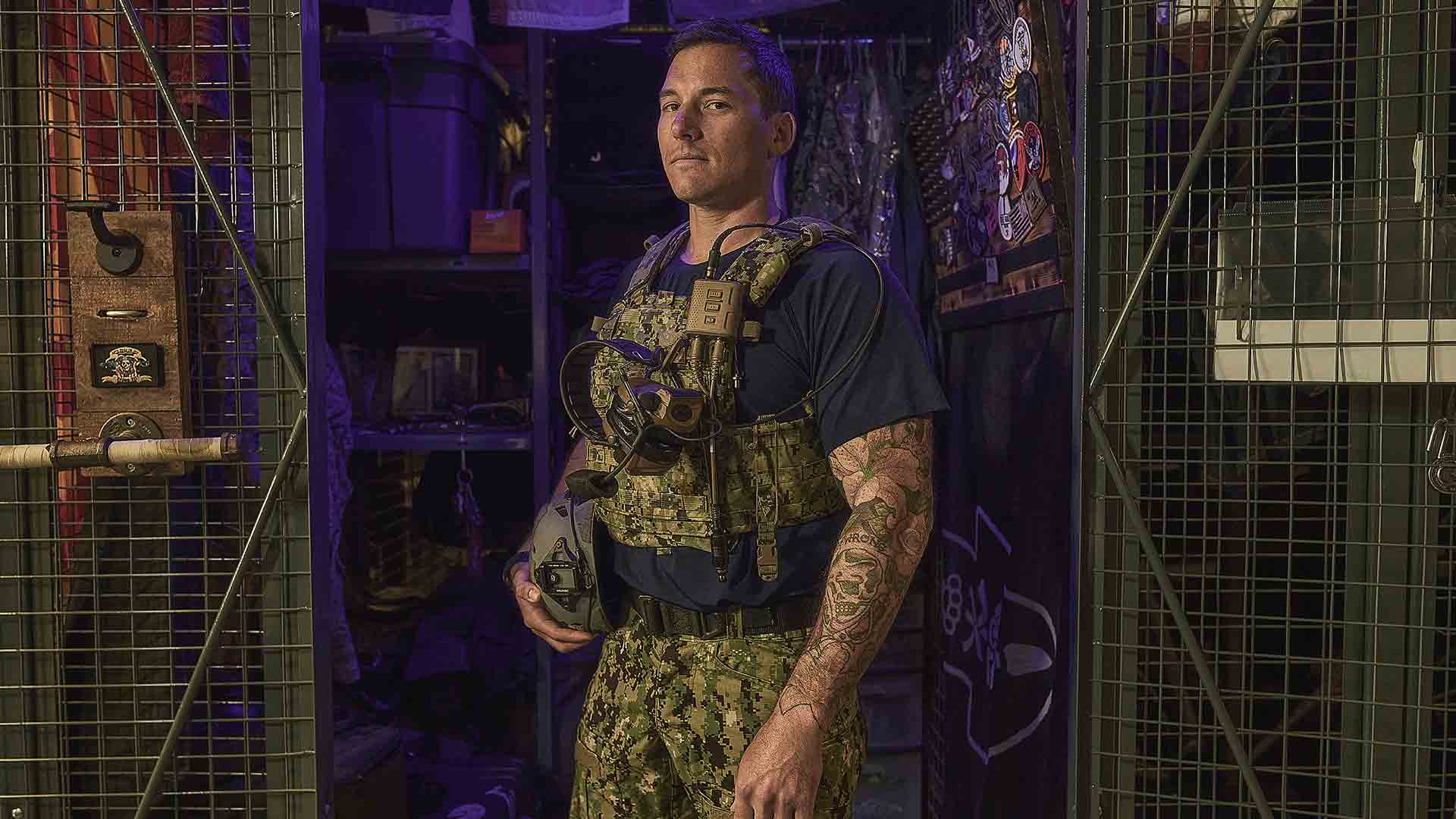 US Navy SWCC sailor SB1 Nick O’Sullivan stands in front of gear locker wearing his Special Warfare Combat Crewman gear.
