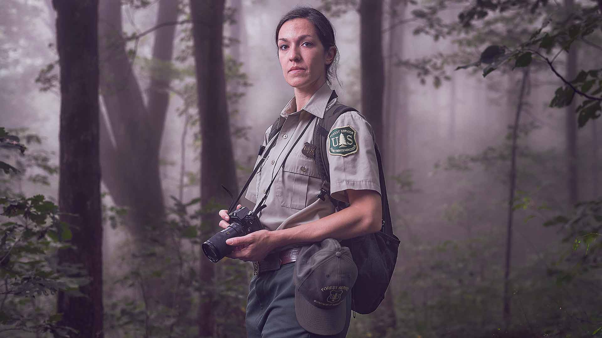 US Navy photographer and mass communications specialist Kathleen Gorby in forest service uniform with camera at the ready.