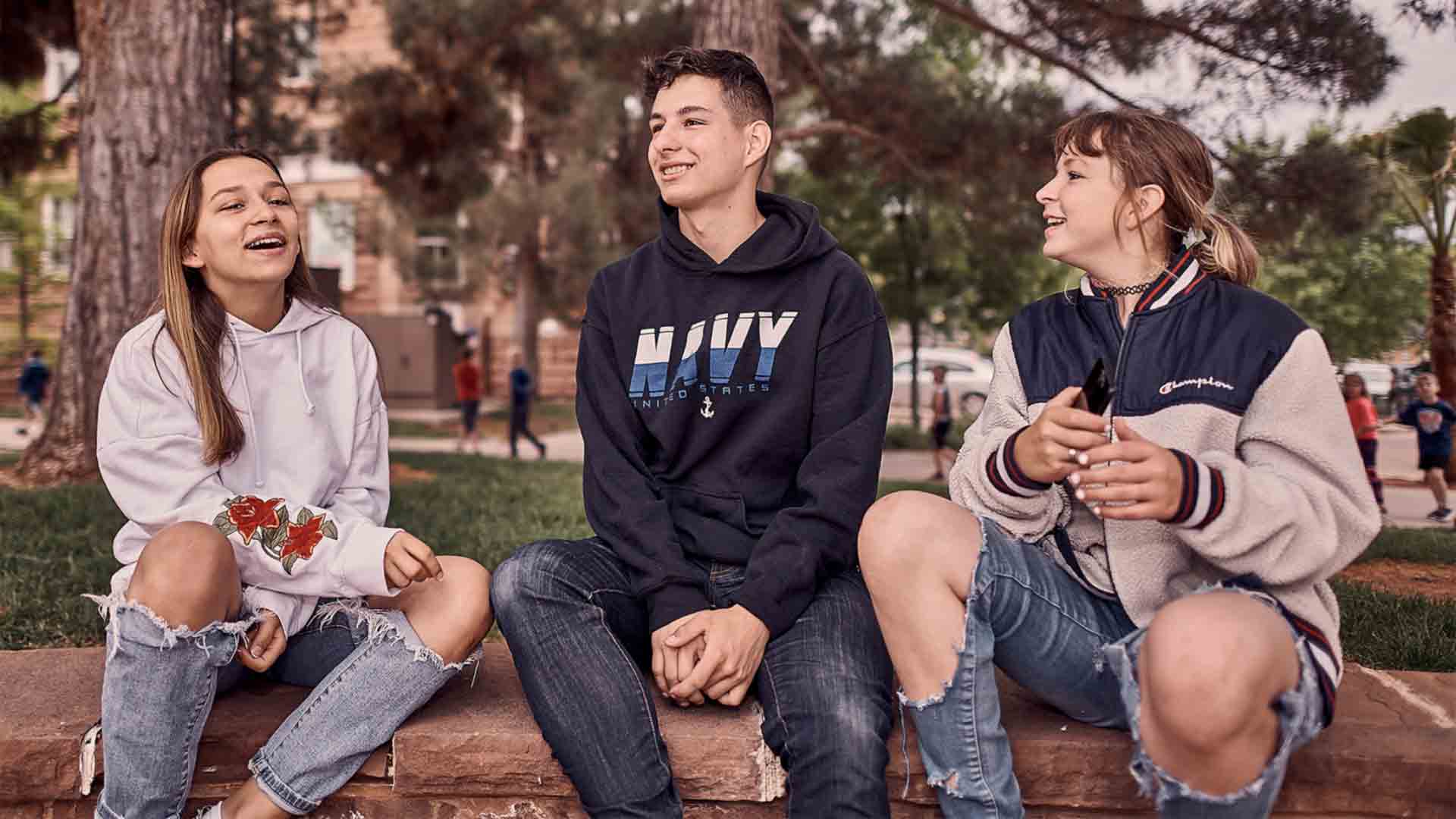 Navy Sailor Thomas Schwab laughs outside at a picnic with his two sisters 