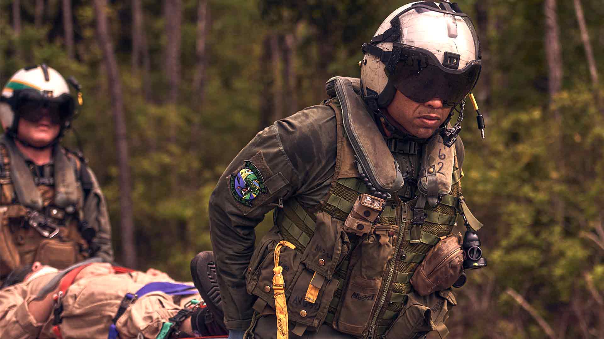 United States Navy Aircrewman Esmelin Villar carries a rescued victim on a stretcher.