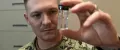 Navy Industrial Hygiene Officer examines a specimen in a glass bottle