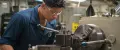 A United States Navy Machinery Repairman operates a milling machine aboard the USS Chung-Hoon.