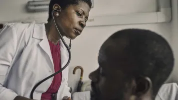 Navy doctor carefully examining a patient, listening to their chest with a stethoscope for diagnosis.