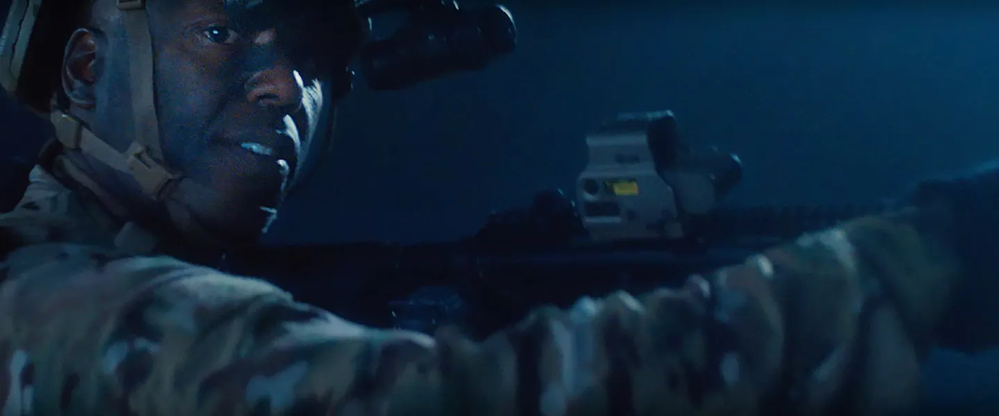 United States Navy Sailor in combat gear at night looks at camera.