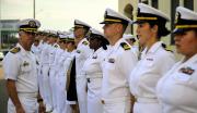 United States Navy Sailors in summer white service uniforms stand at attention.